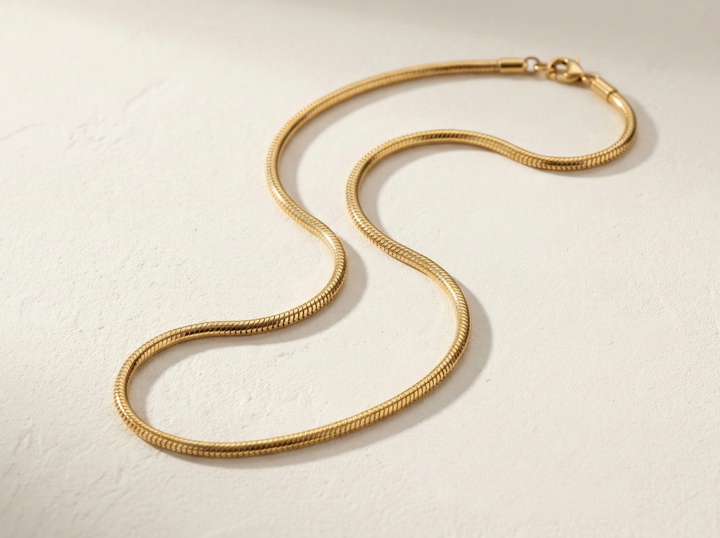 L'Eclat gold necklace flatlay in soft S-curve