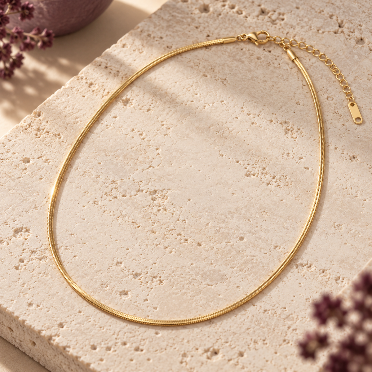 Gold L’Éclat necklace on travertine